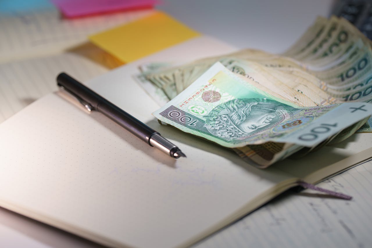 services-03 Close-up of Polish Zloty banknotes on an open notebook with a pen, symbolizing finance and budgeting.